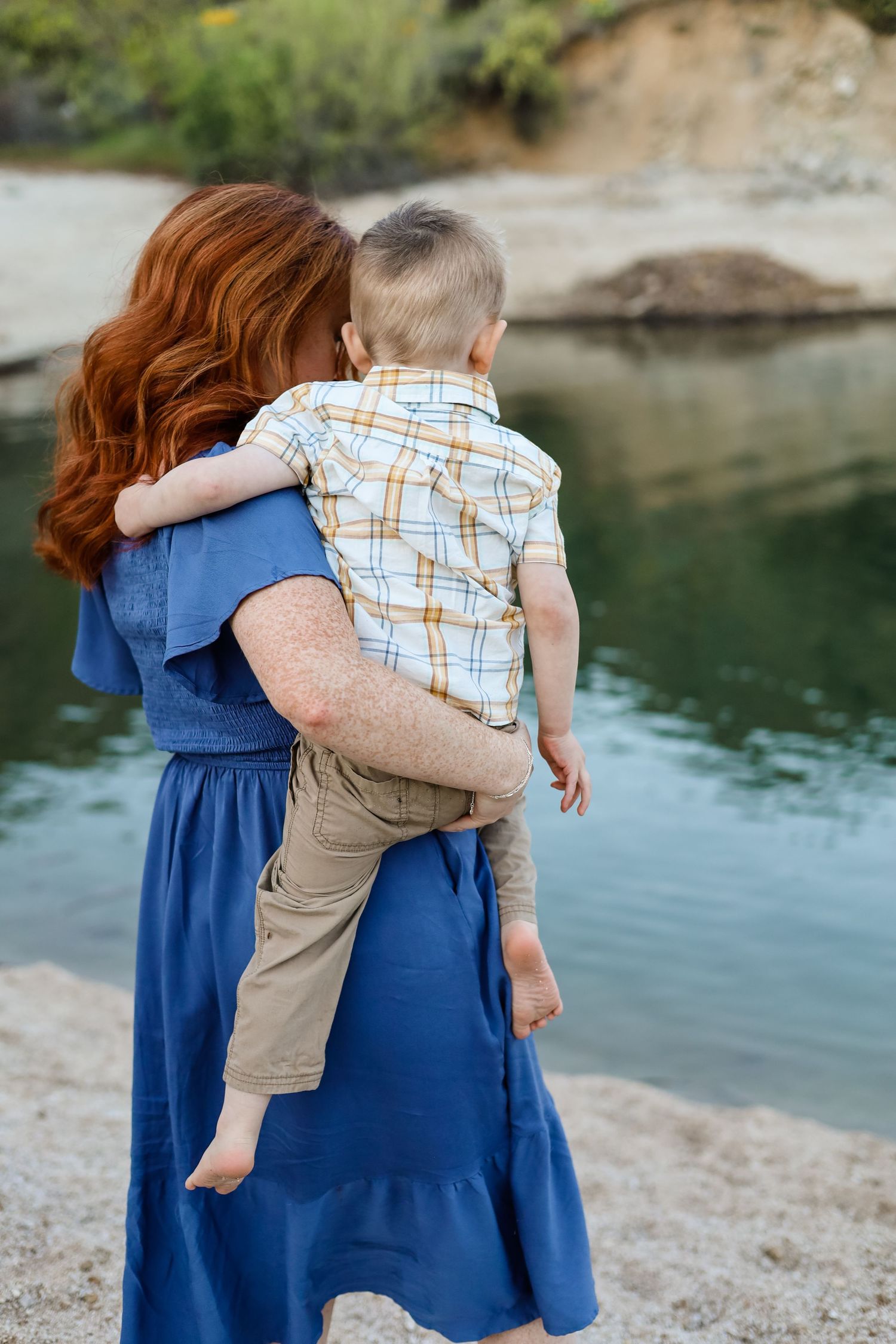 A tender moment captured by the water's edge in blue dress and casual attire.