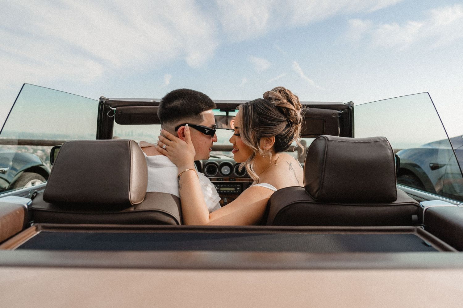 Couple sharing intimate moment in convertible car during sunset.