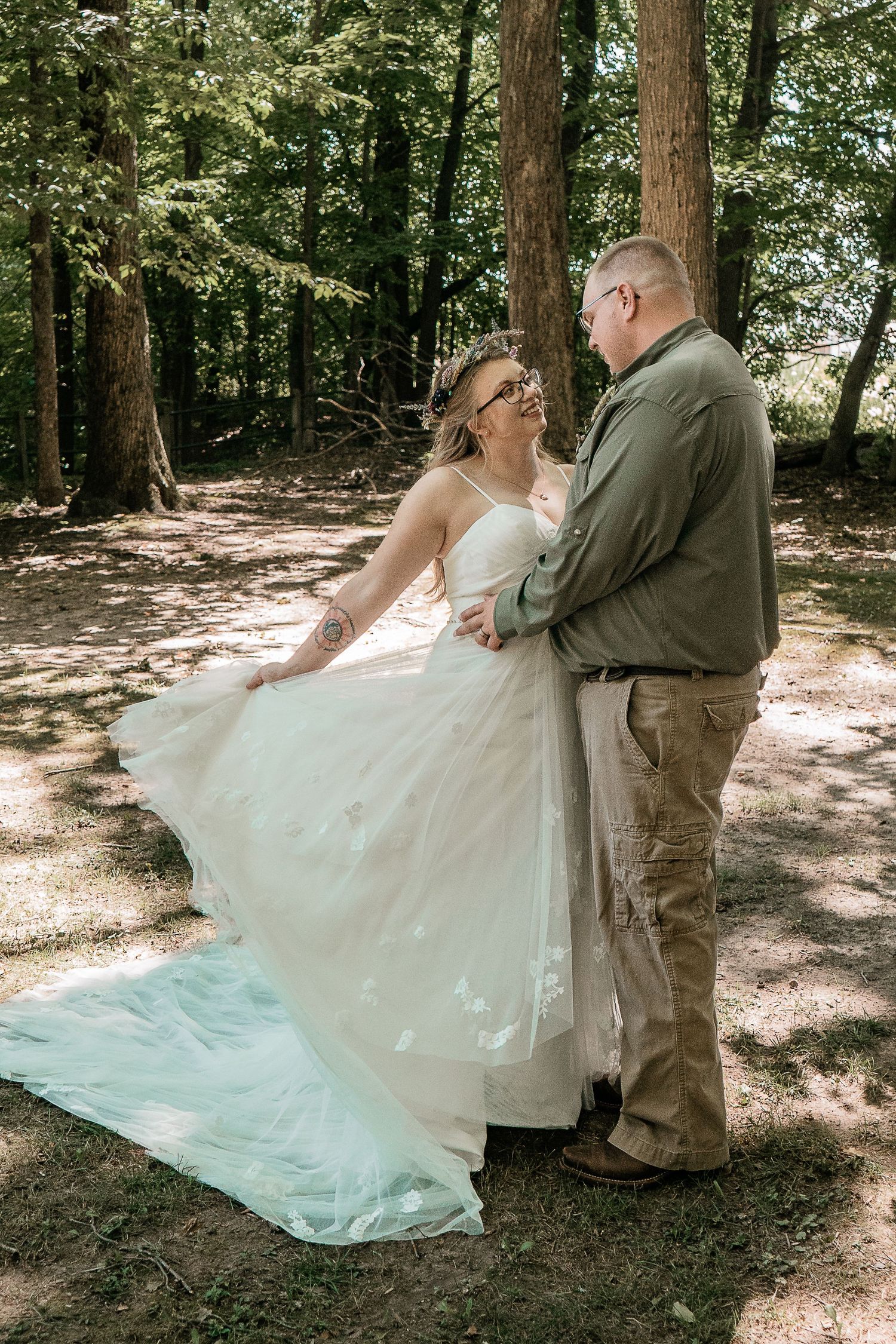 A couple in wedding attire share an intimate moment, with the bride wearing a sparkly dress and groom in light gray suit.
