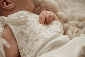 A close-up detail shot of intricate white lace and beading on a wedding dress.