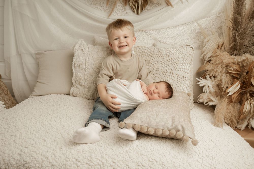 A collection of sepia-toned photographs arranged in a horizontal collage showing tender family moments on textured fabric.