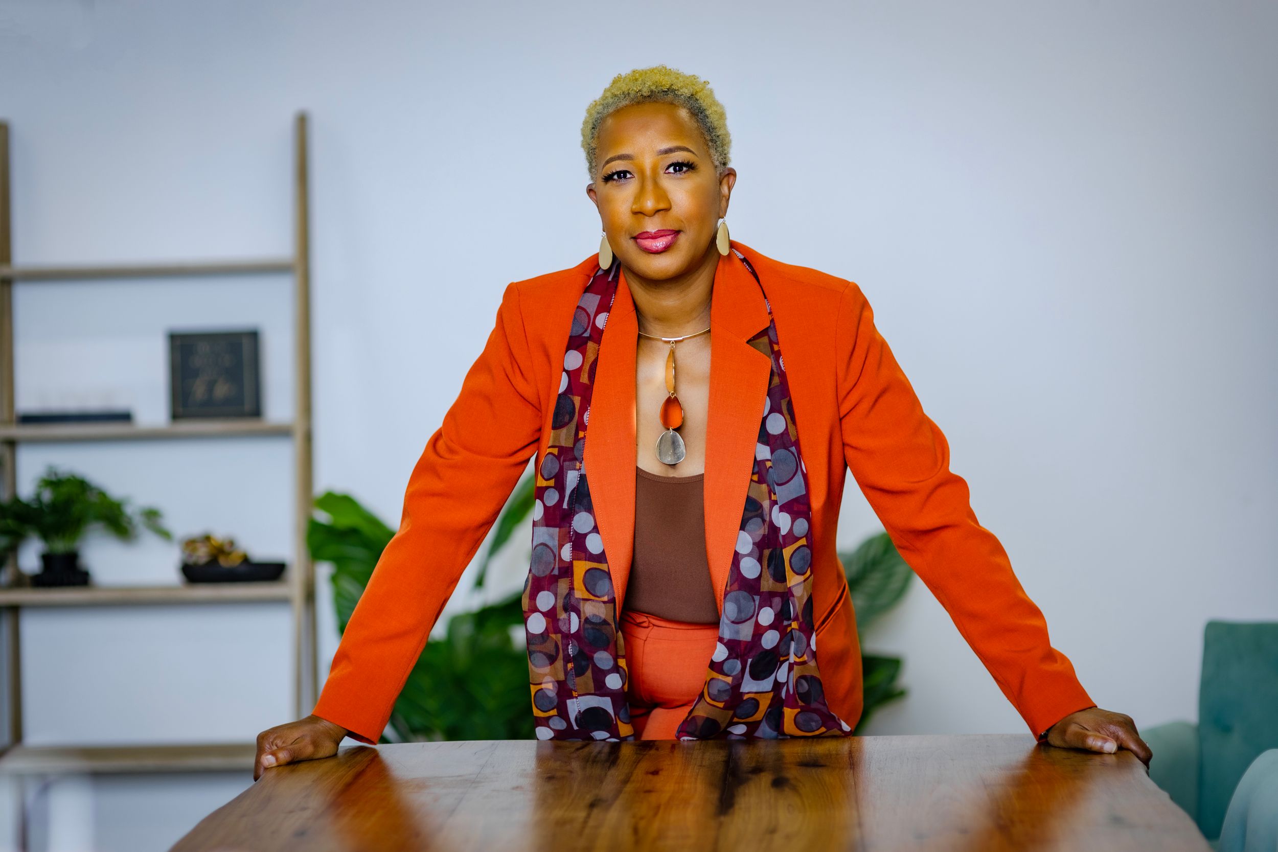 Professional portrait session featuring bright orange business attire and floral scarf against white backdrop.