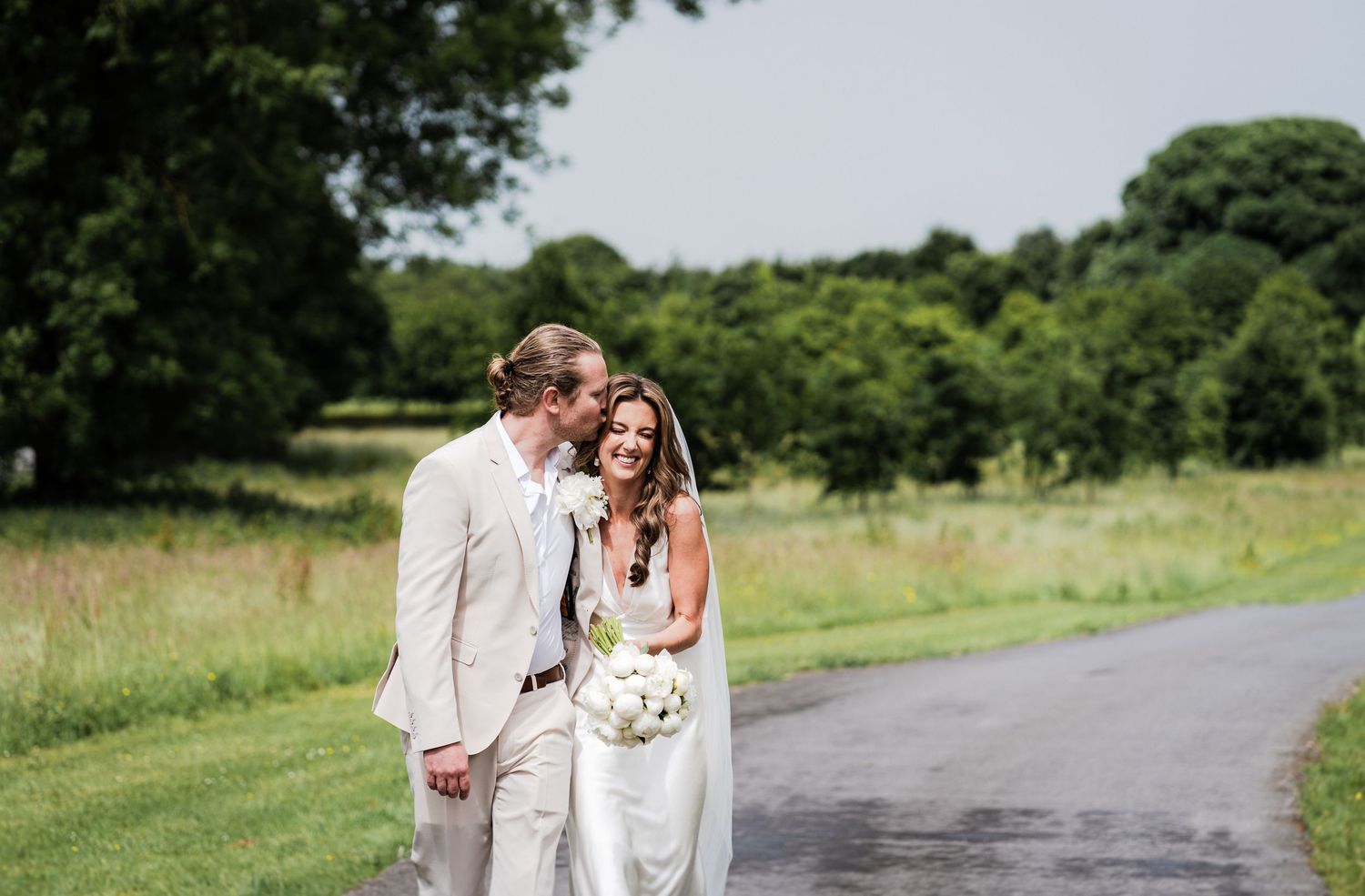A rustic barn wedding entrance with a couple exiting through an arched wooden doorway framed by lush greenery.