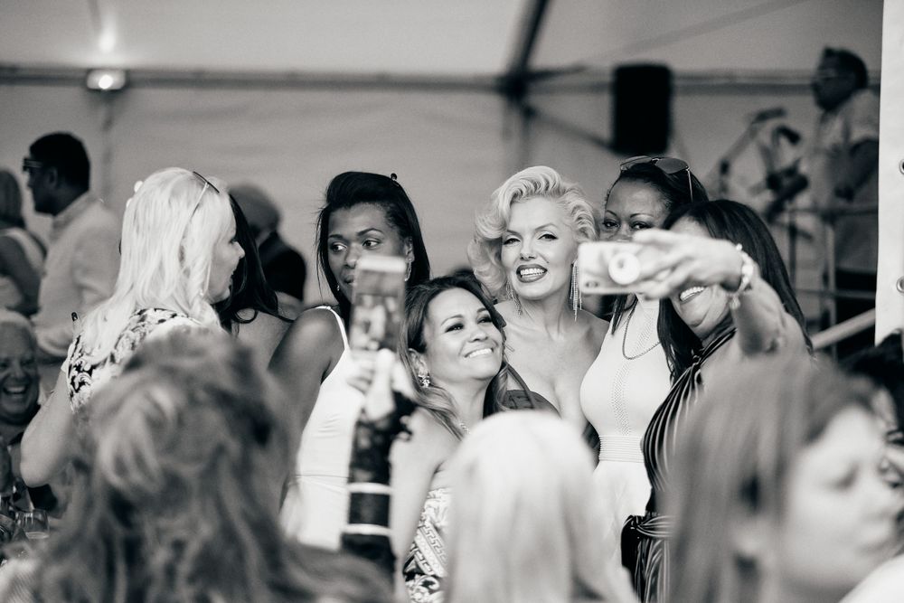 Candid black and white photo of guests laughing and celebrating at a lively wedding reception.