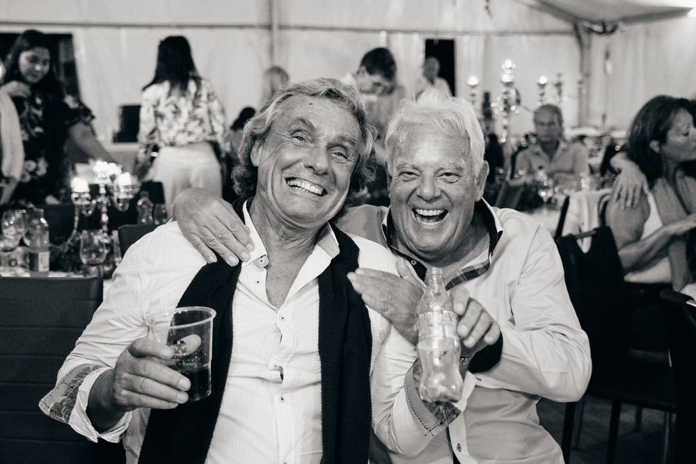Two guests sharing drinks and laughs at an outdoor celebration event.