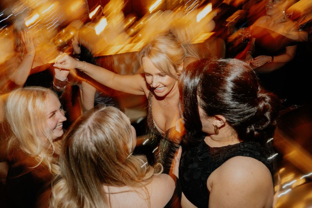 Group of friends dancing and celebrating with motion blur effects at a party.