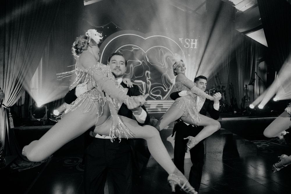 Vintage black and white photo of performers in feathered costumes dancing on stage.