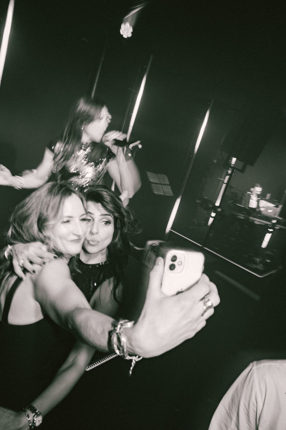 Black and white party photo showing friends taking selfies in a dimly lit venue.