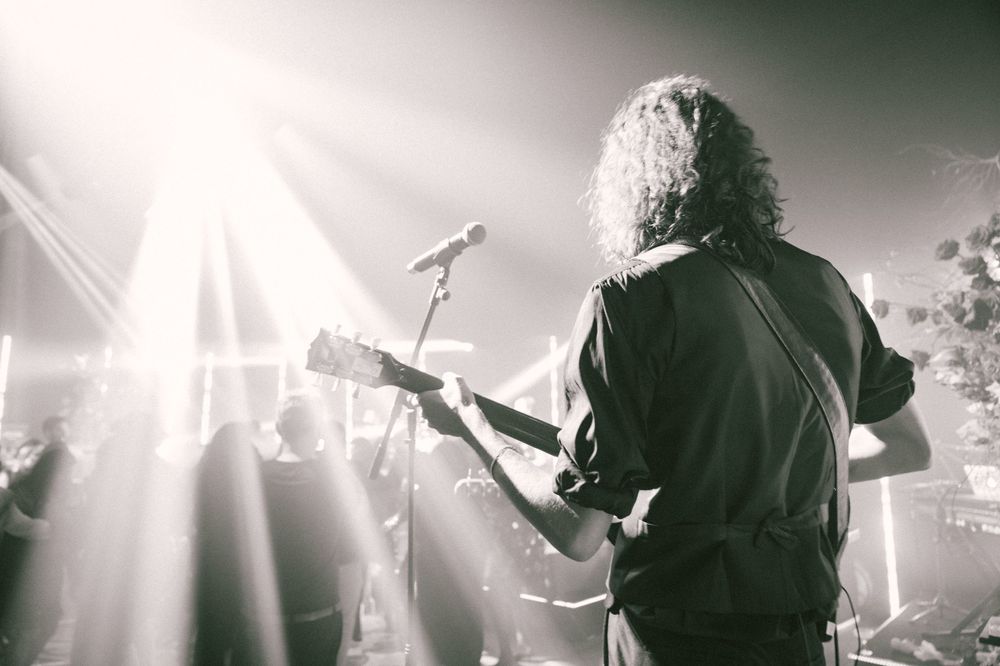 Silhouette of musician performing on stage with dramatic backlighting and fog effects.