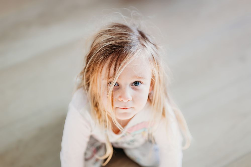 Close-up portrait of a young child with blonde hair looking directly at camera.