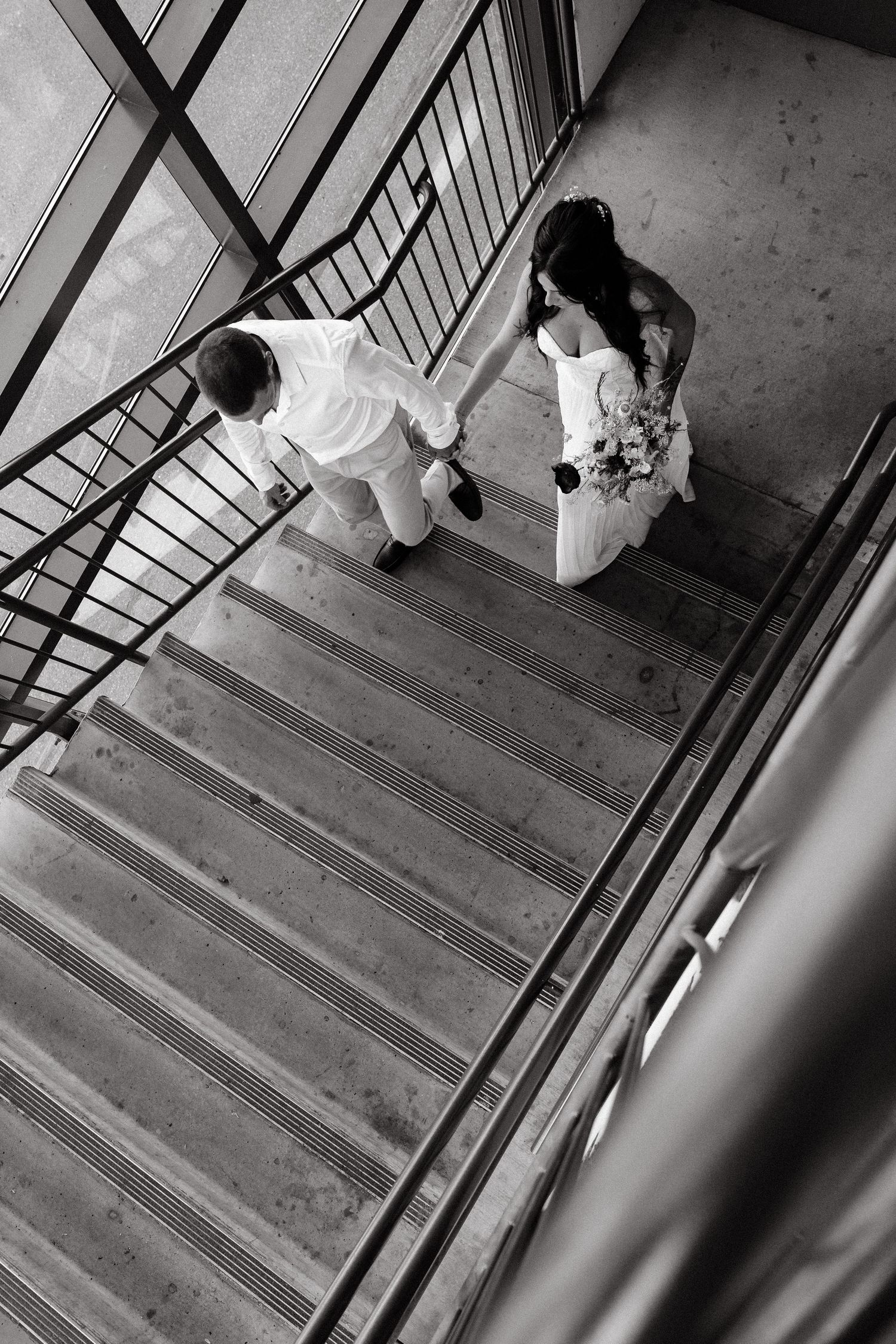 Black and white overhead view of a couple descending stairs.