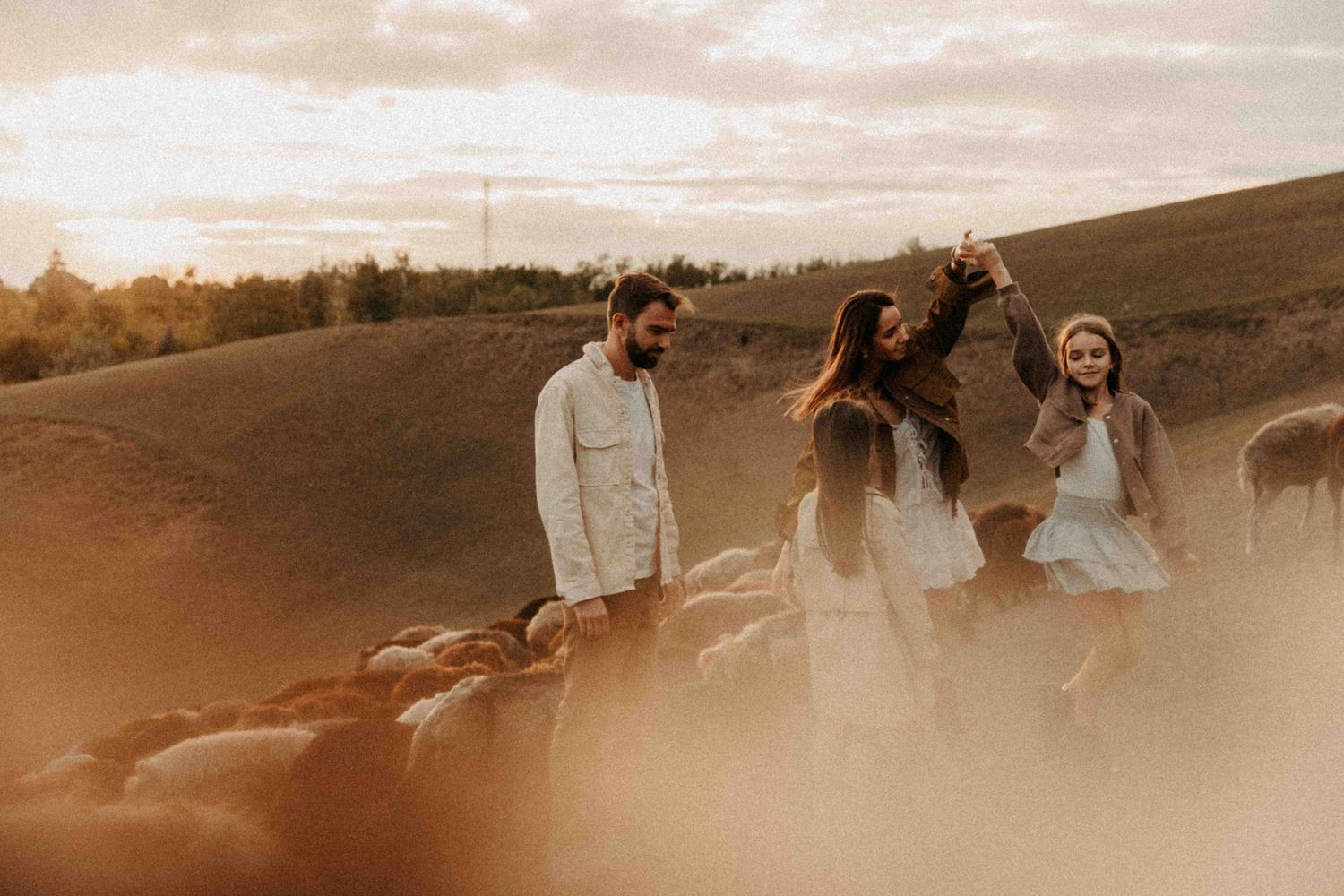 Group of people enjoying sunset on a hillside in warm sepia tones during golden hour.