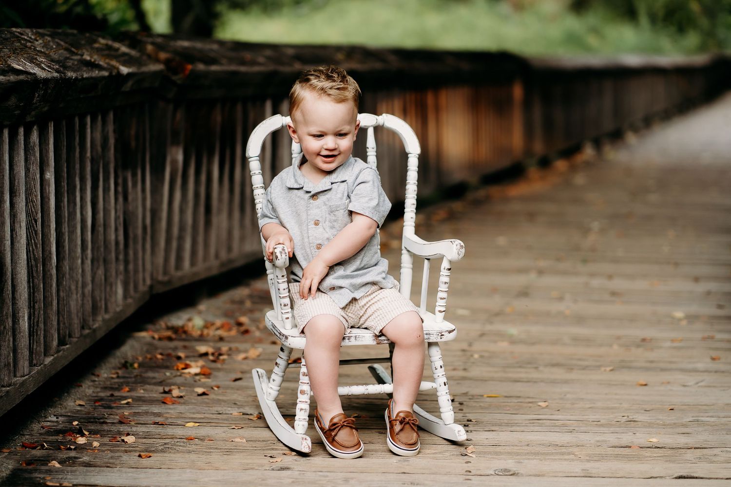 Toddler boy sits in rocking chair on the boardwalk at Nisqually Wildlife Refuge for summer family photos.