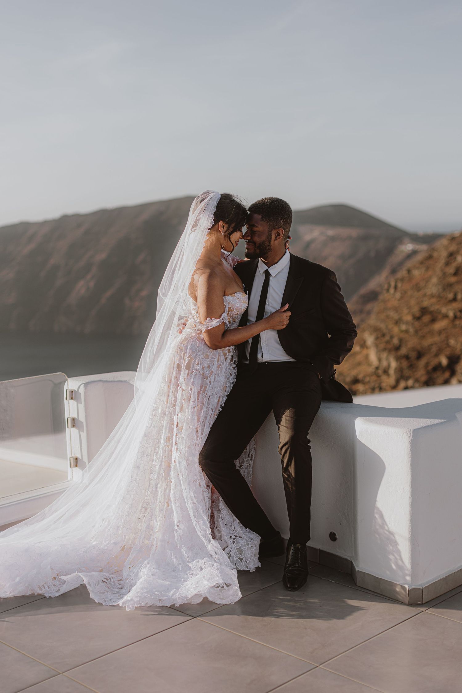 Romantic wedding couple sharing intimate moments against a mountain backdrop.