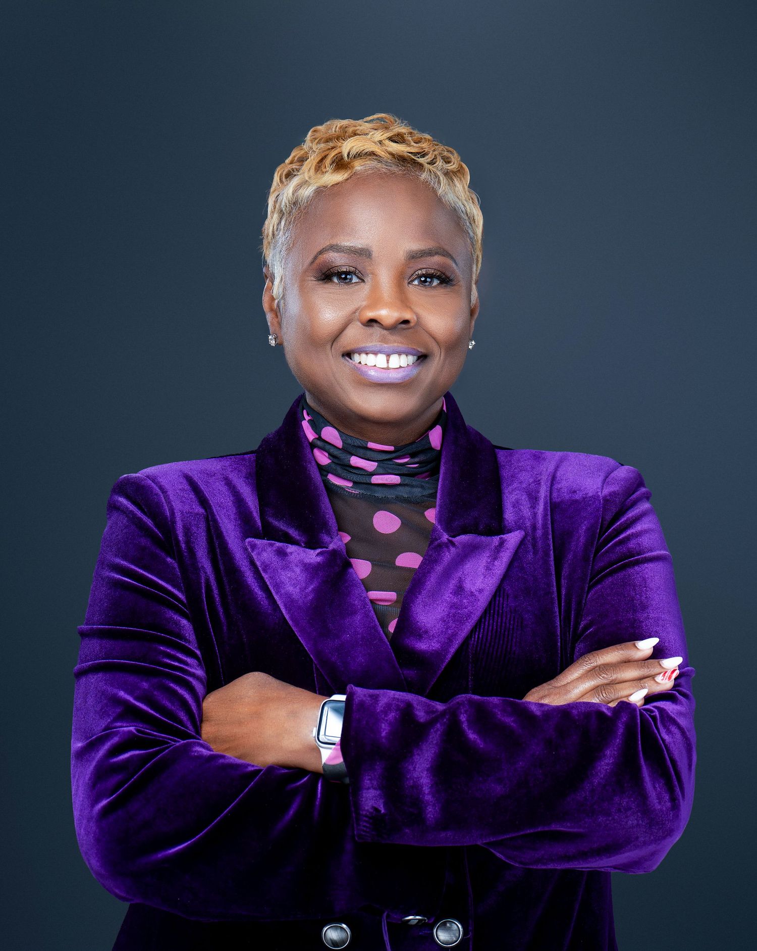 Studio portraits featuring performer wearing purple velvet jacket against dark backdrop.