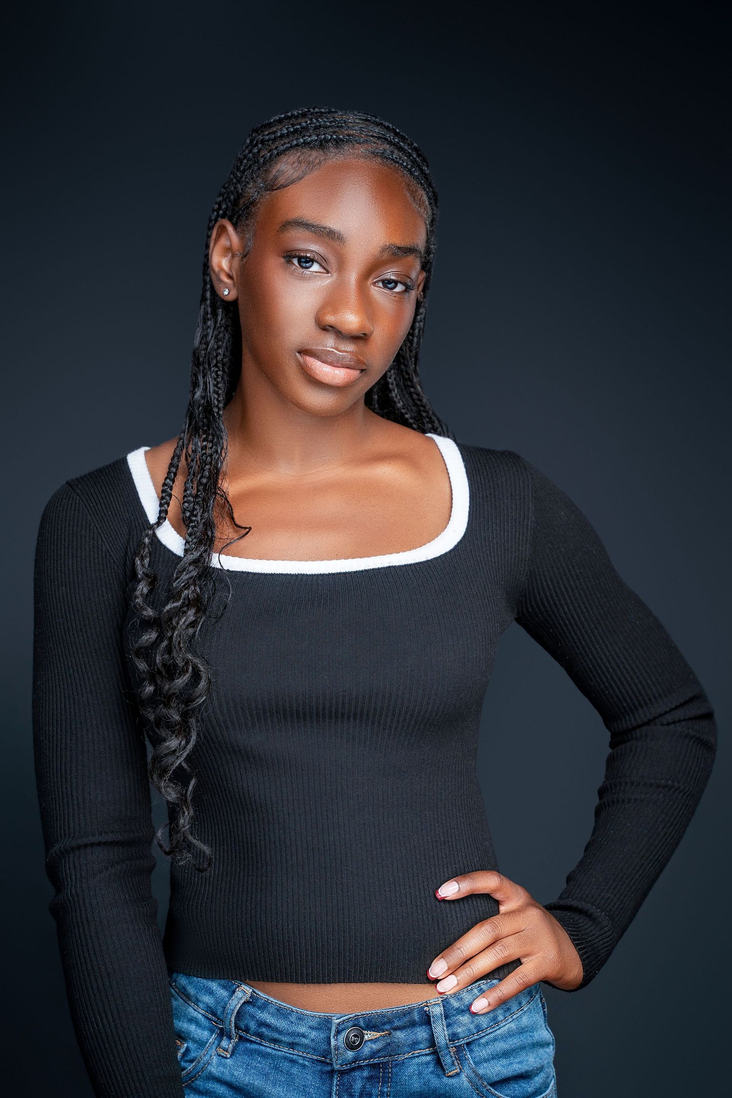 Fashion portraits showing model in black crop top and jeans against dark background.
