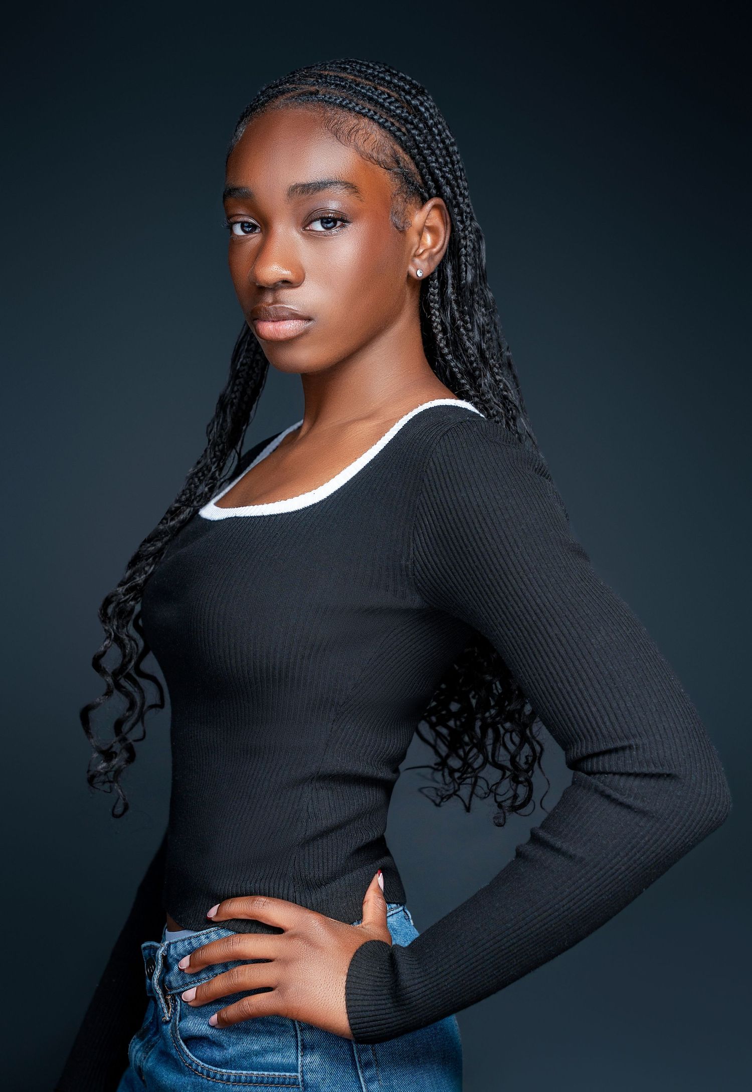 Fashion portraits featuring model in black sweater and jeans against dark backdrop.