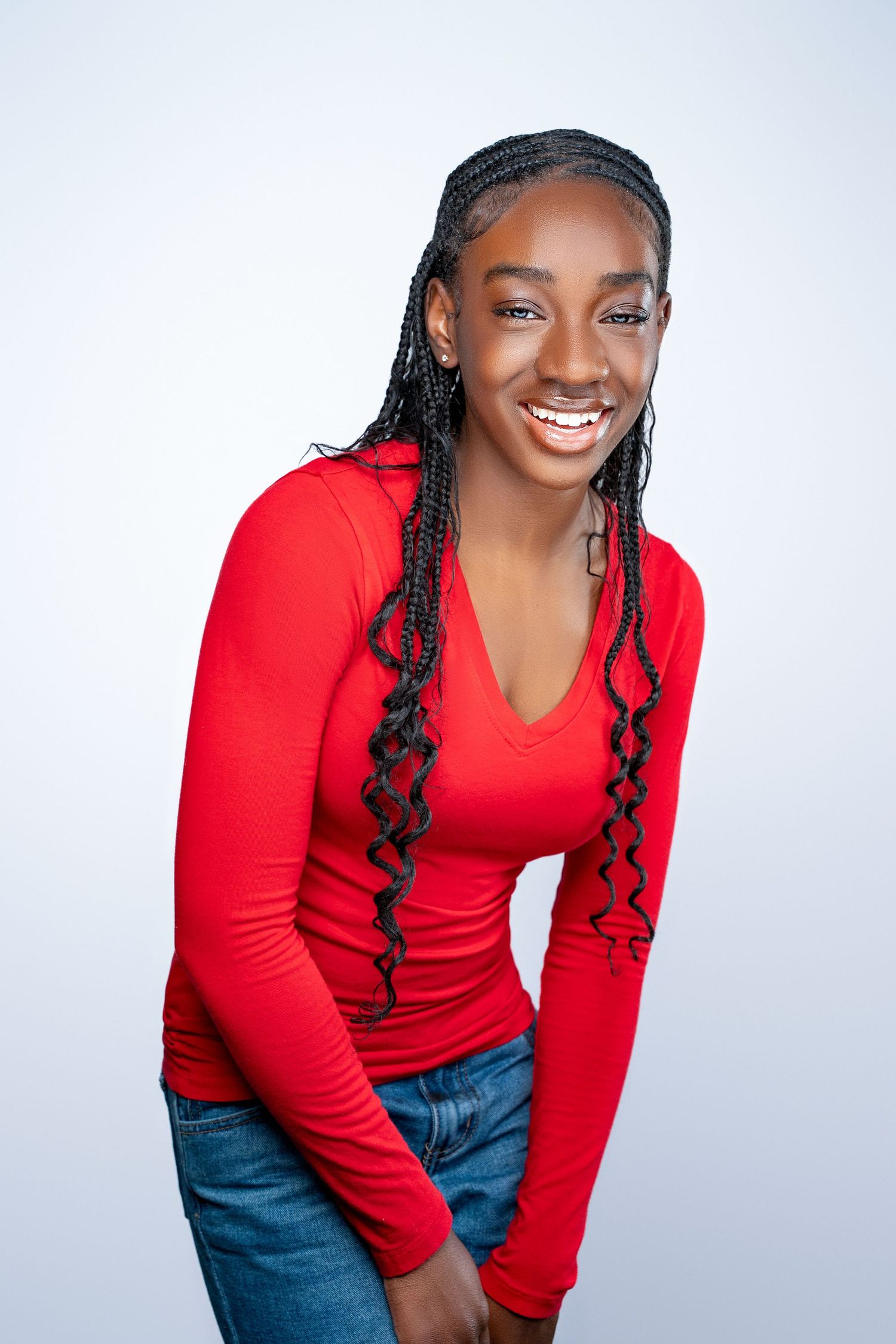 Lifestyle portraits featuring model in red long sleeve top and jeans against white background.