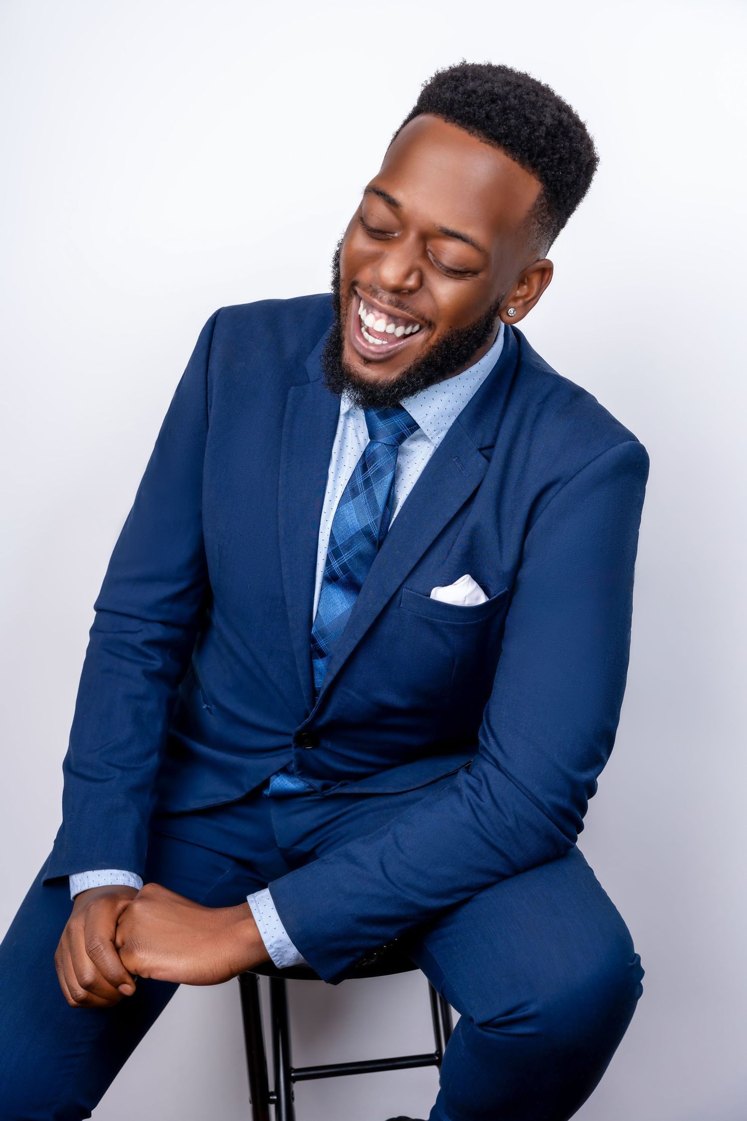 Multiple poses of person in navy suit and tie showing joyful expressions against white backdrop.