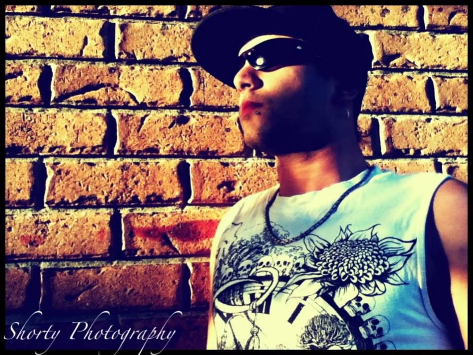 Close-up portrait of someone wearing a white t-shirt against a rustic brick wall with vintage photographic effects.