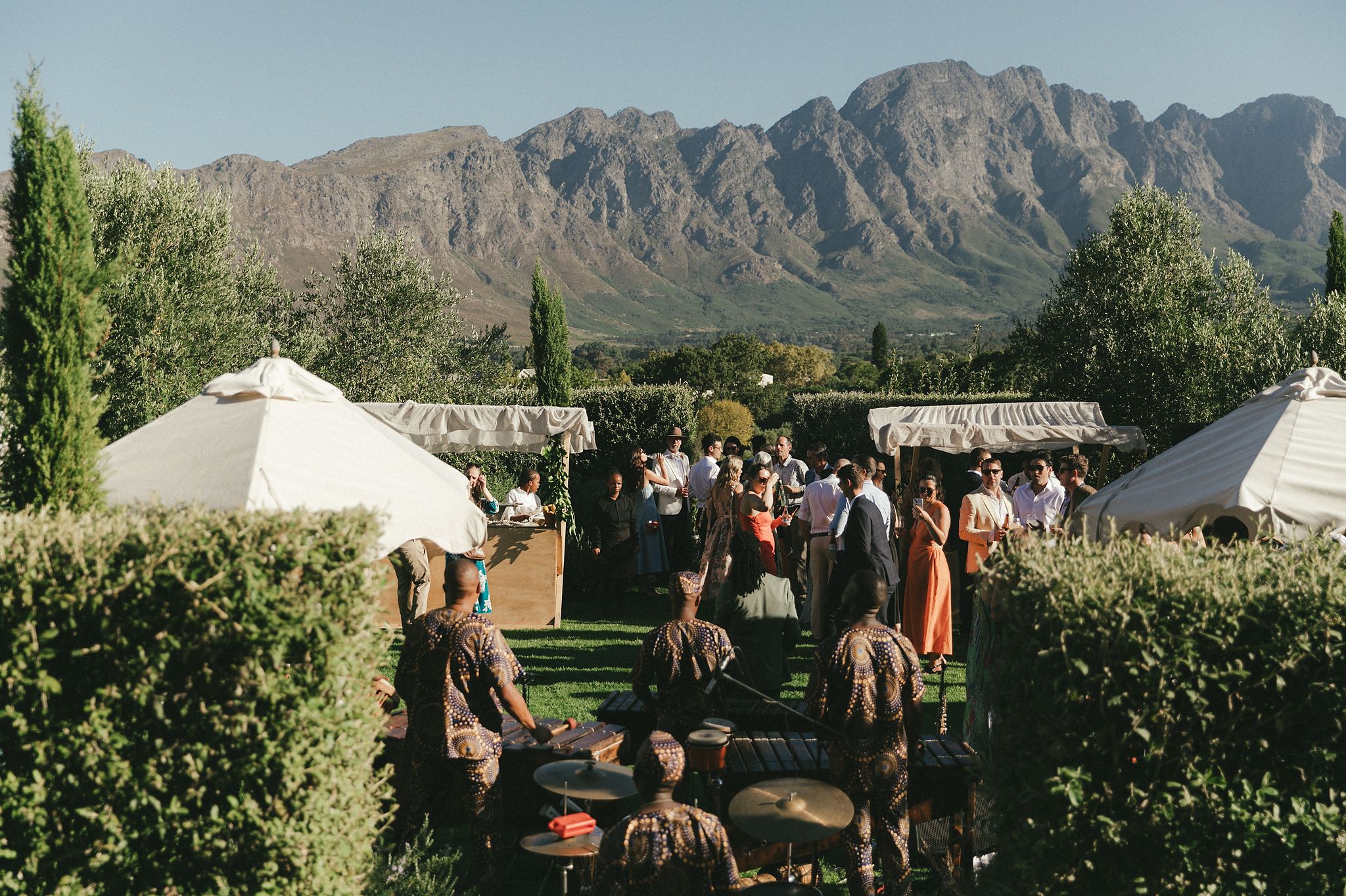 Wedding guests enjoying pre-drinks in the gardens at La Cotte, Cape Winelands