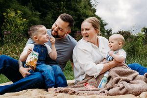 A family sitting together outdoors on a blanket enjoying precious candid moments during a photoshoot.