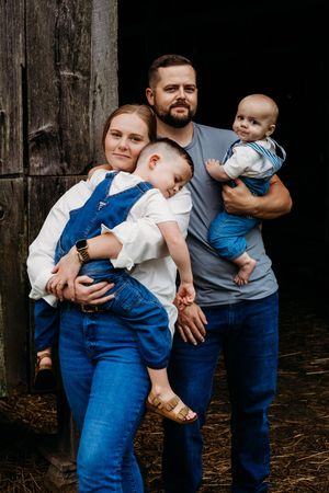 A series of candid family moments captured against a dark wooden barn setting.