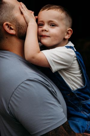 A close-up sequence of a tender parental embrace showing comfort and emotional connection in a dark setting.