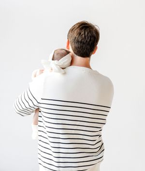 Someone wearing a white and black striped sweater shown from behind in a series of poses against a white background.