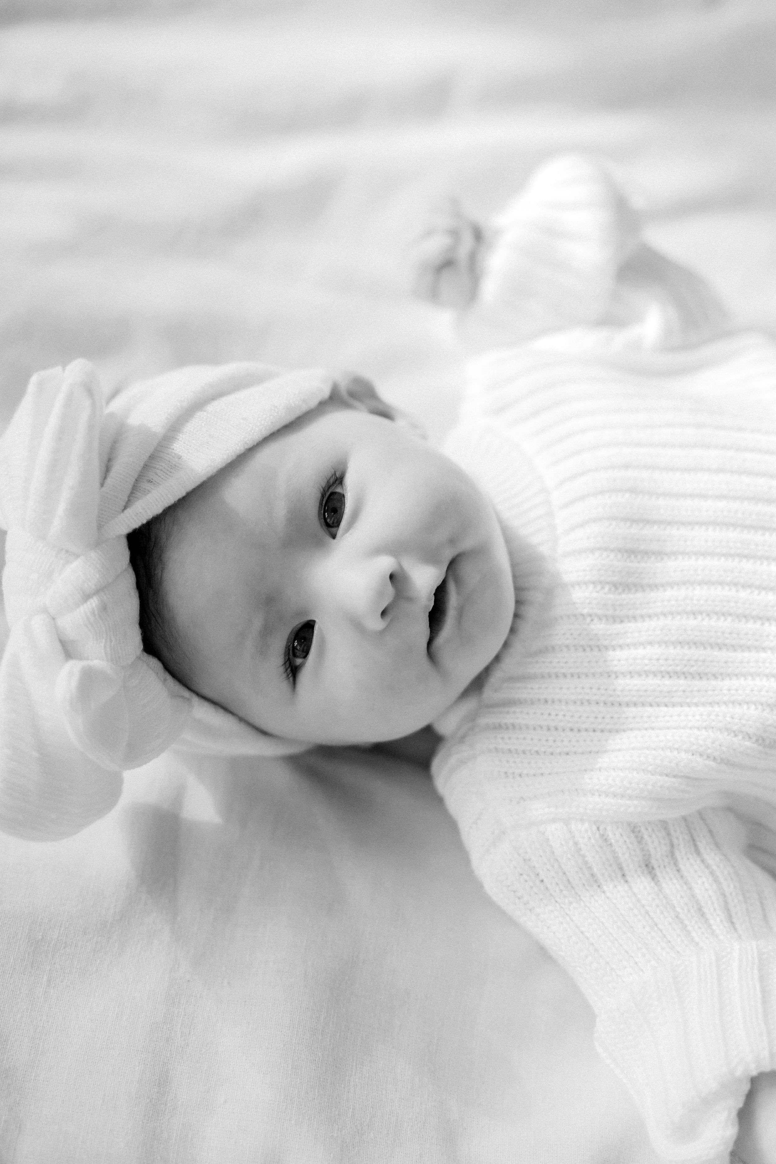 High-key black and white portrait series showing a baby in a white knit sweater against a light background.