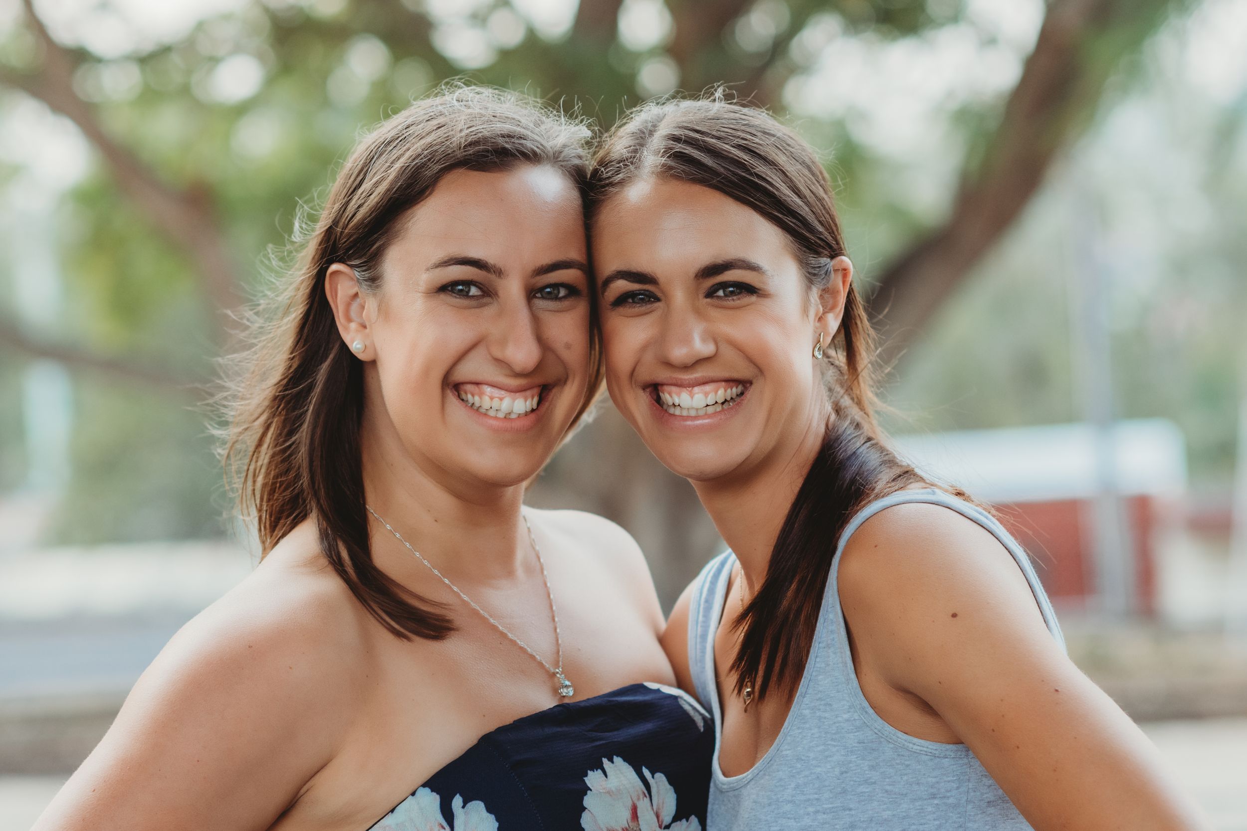 Two friends sharing a joyful moment together outdoors on a sunny day.
