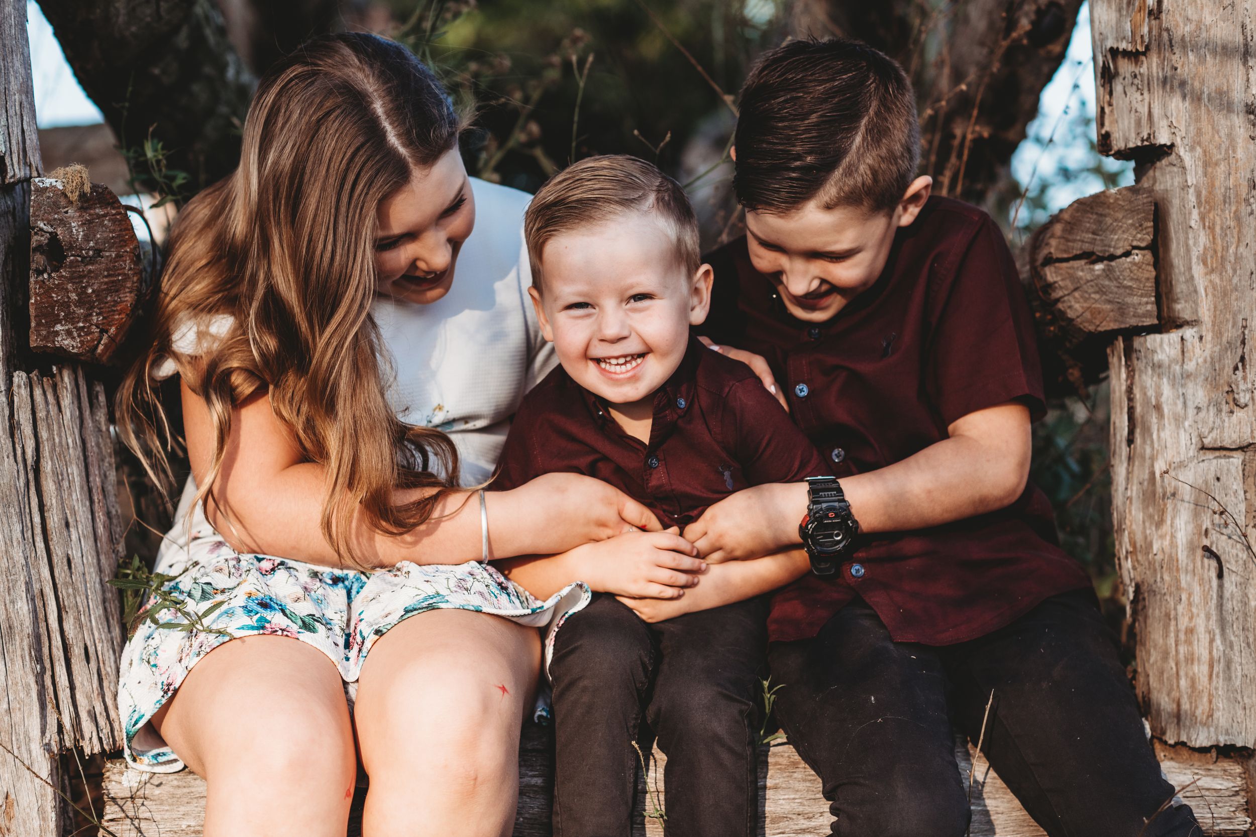 Family sharing cheerful moment together on rustic wooden bench outdoors.
