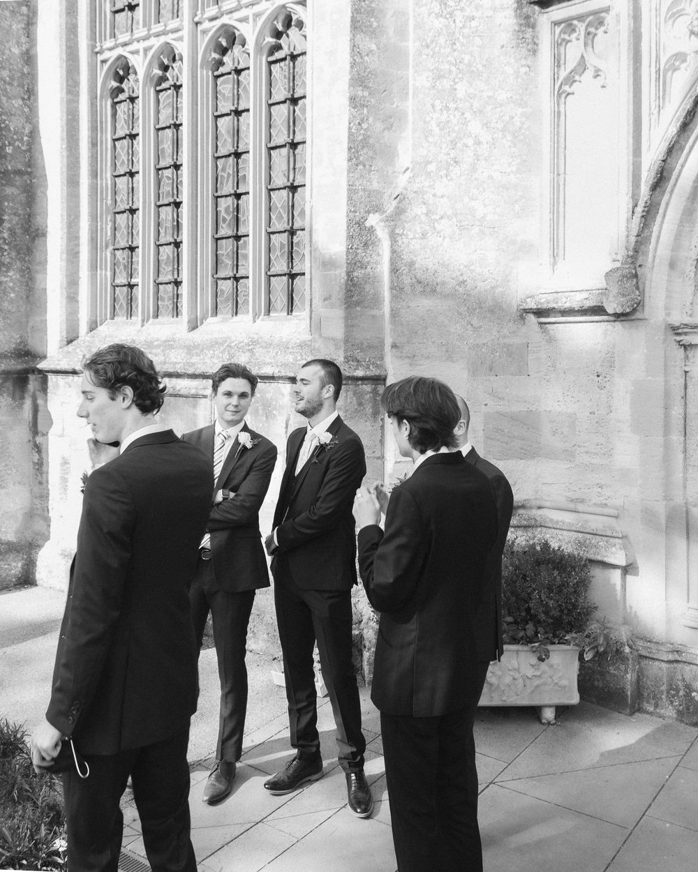 A black and white photo of people gathered outside a Gothic church building with tall arched windows.