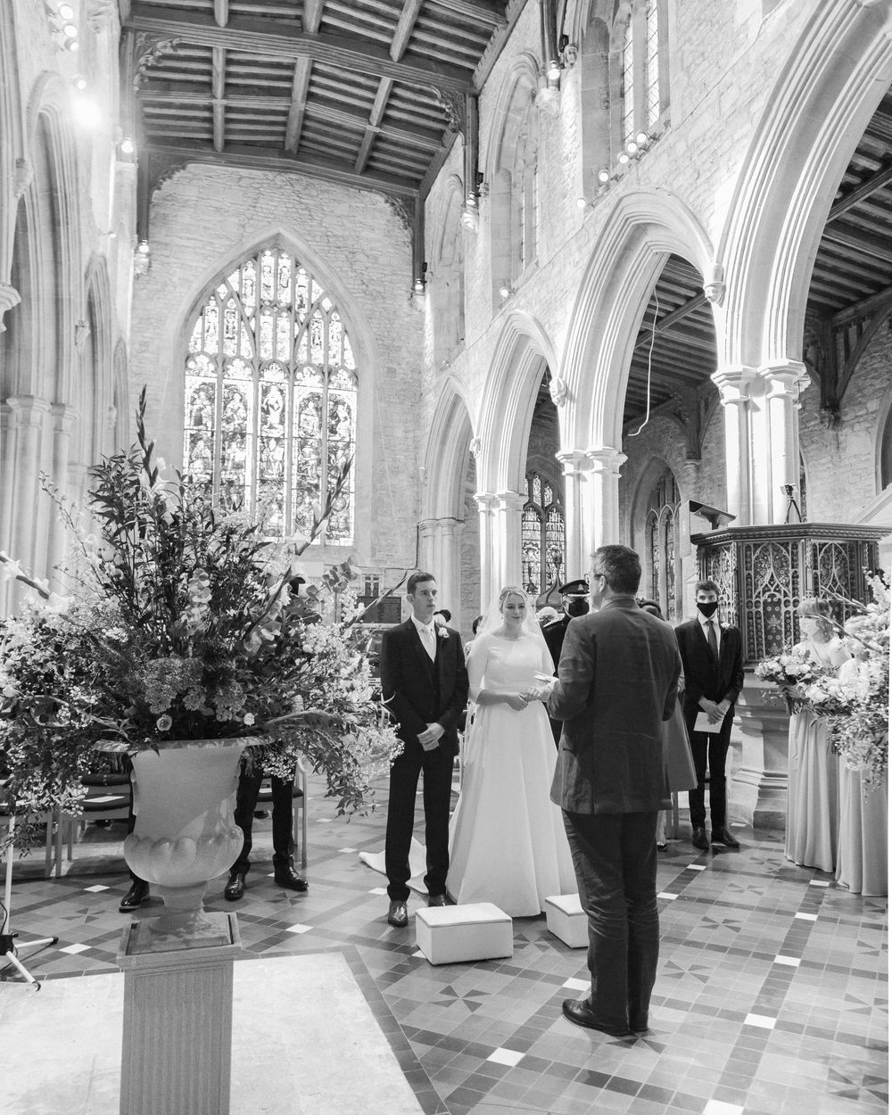 A wedding ceremony taking place in a grand cathedral with stained glass windows and elegant floral arrangements.