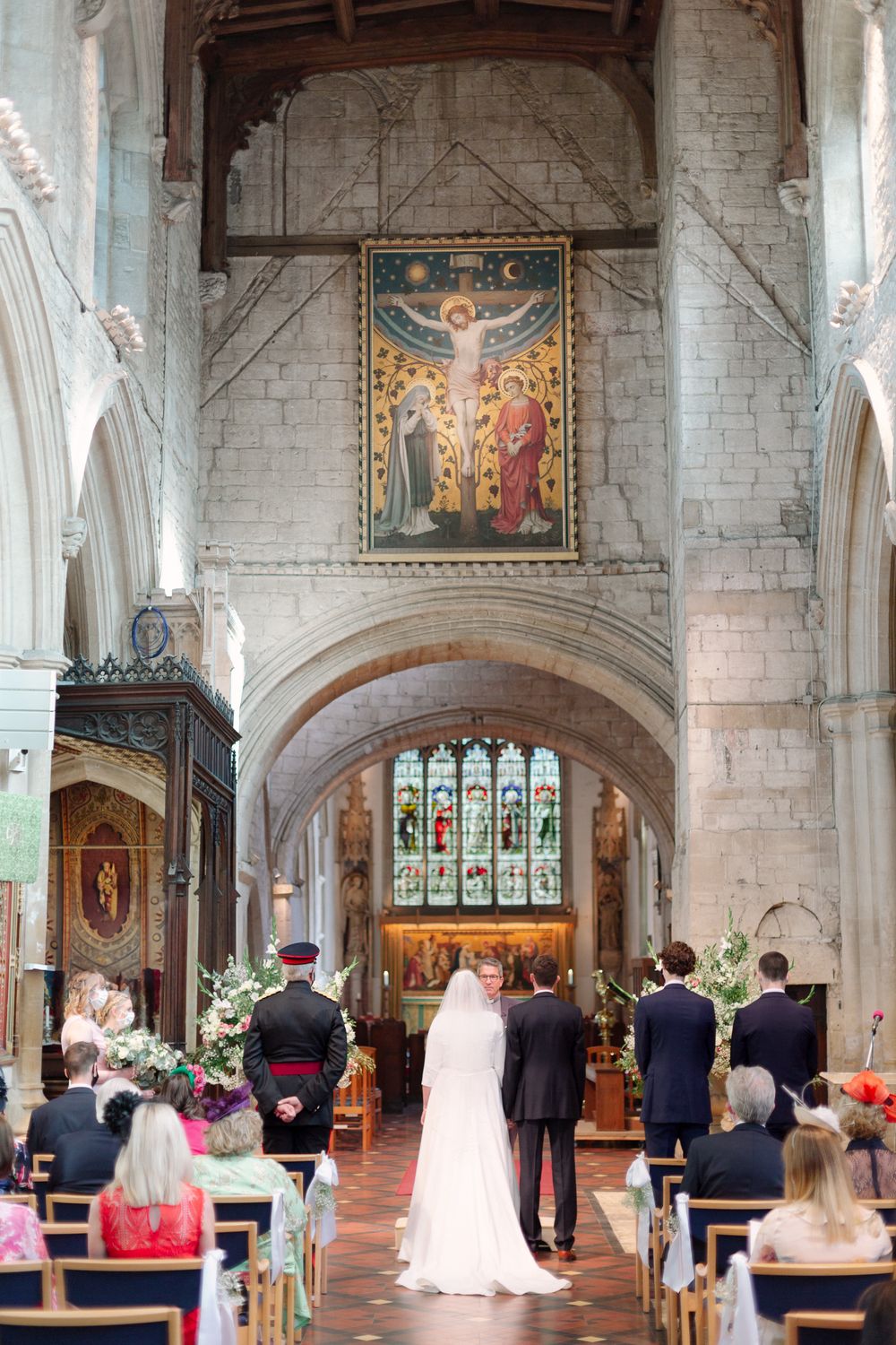 A traditional church wedding ceremony in progress showing the altar, stained glass windows, and gathered guests in pews.