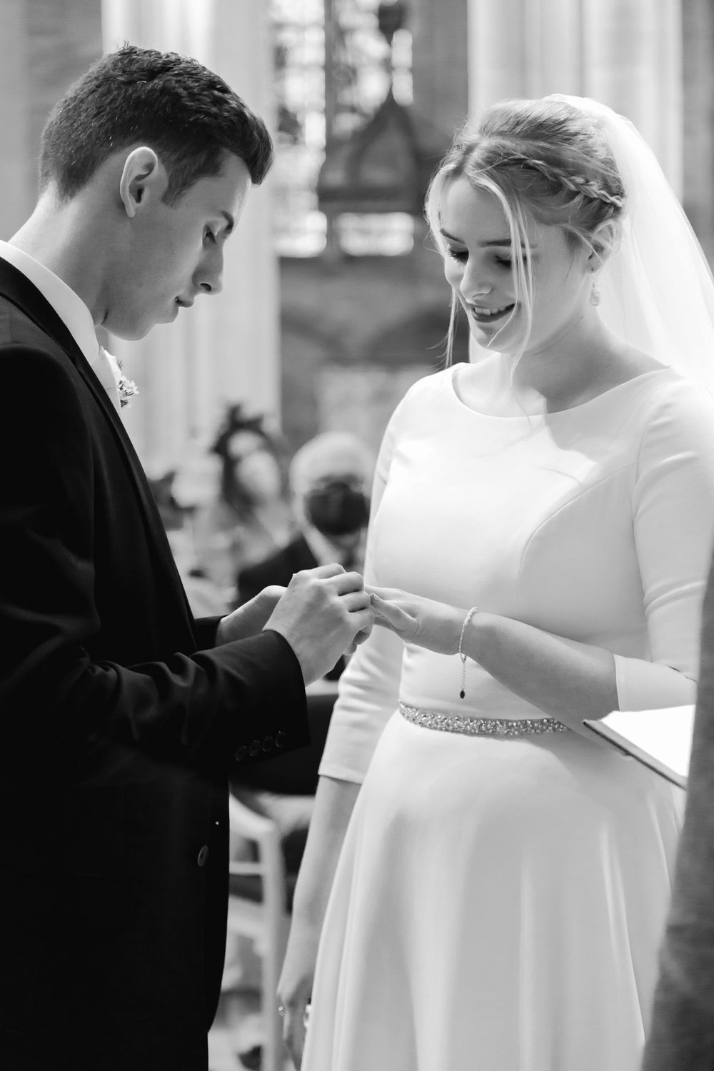 A tender black and white moment as a bride and groom exchange rings during their wedding ceremony.