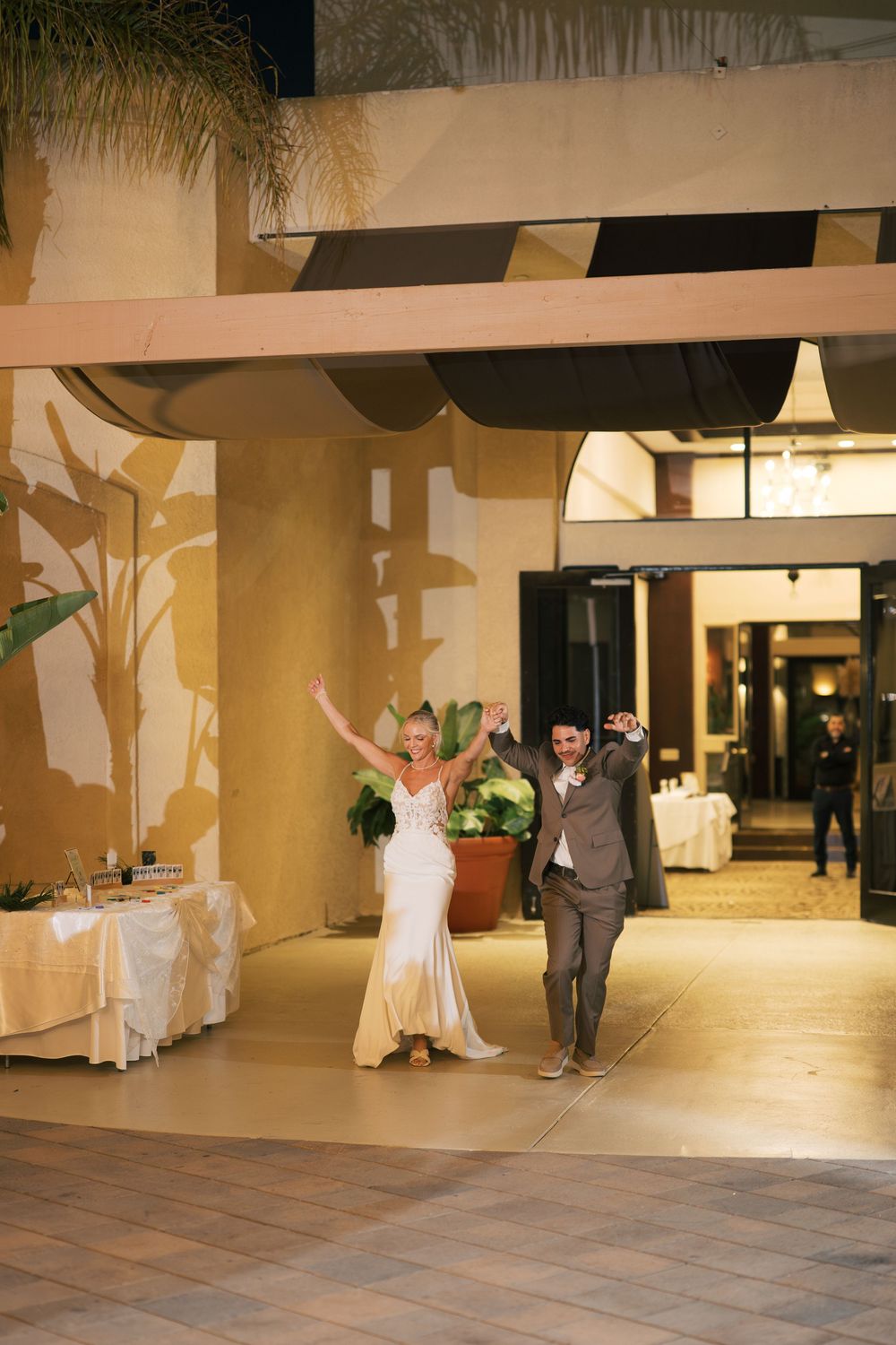 A couple performs a twirling dance move sequence on a spacious indoor dance floor during what appears to be a reception.