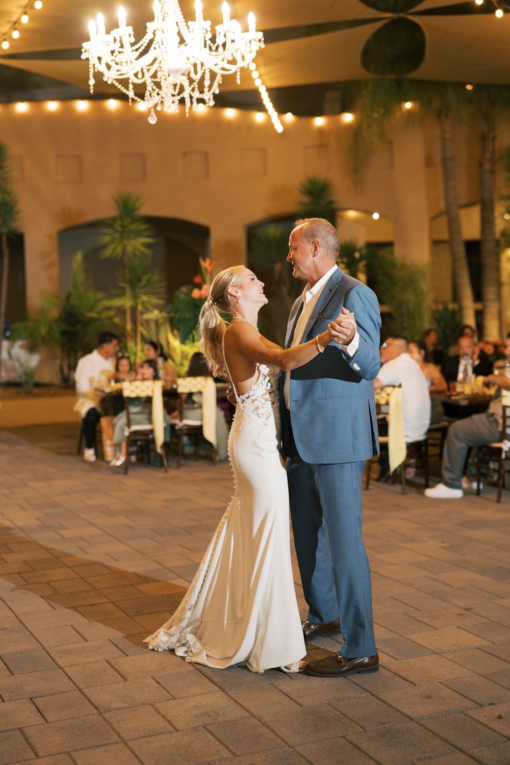 A romantic evening dance under a crystal chandelier at an elegant wedding reception venue.