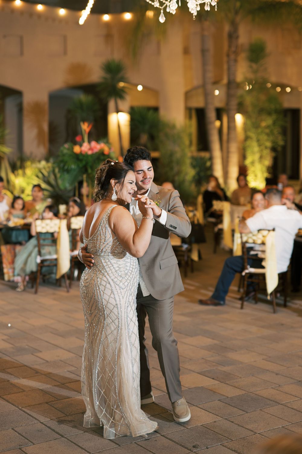 Wedding reception dance floor scene with romantic lighting and palm trees at an indoor venue.