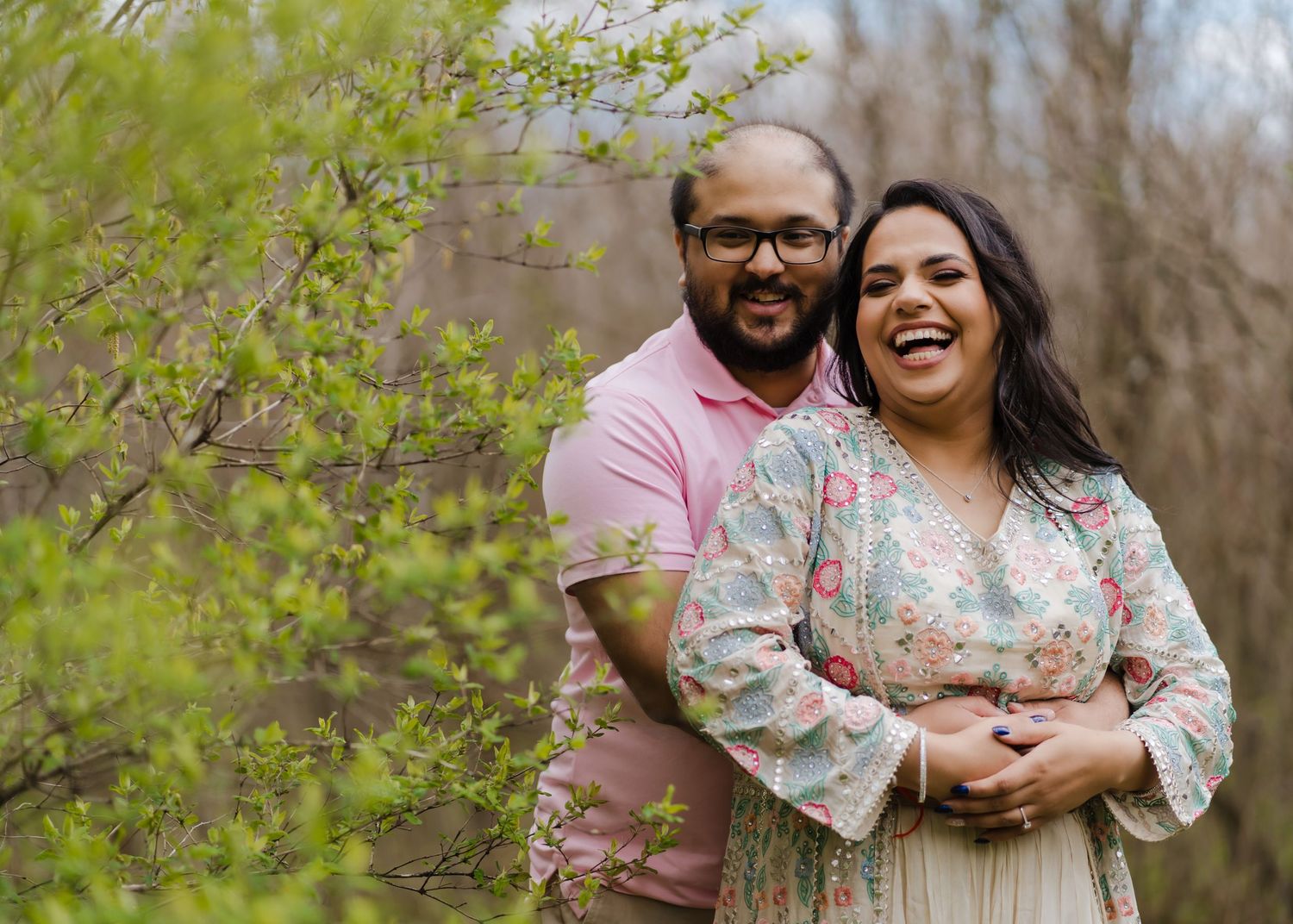 A happy couple shares a tender moment among spring blossoms in a natural outdoor setting.