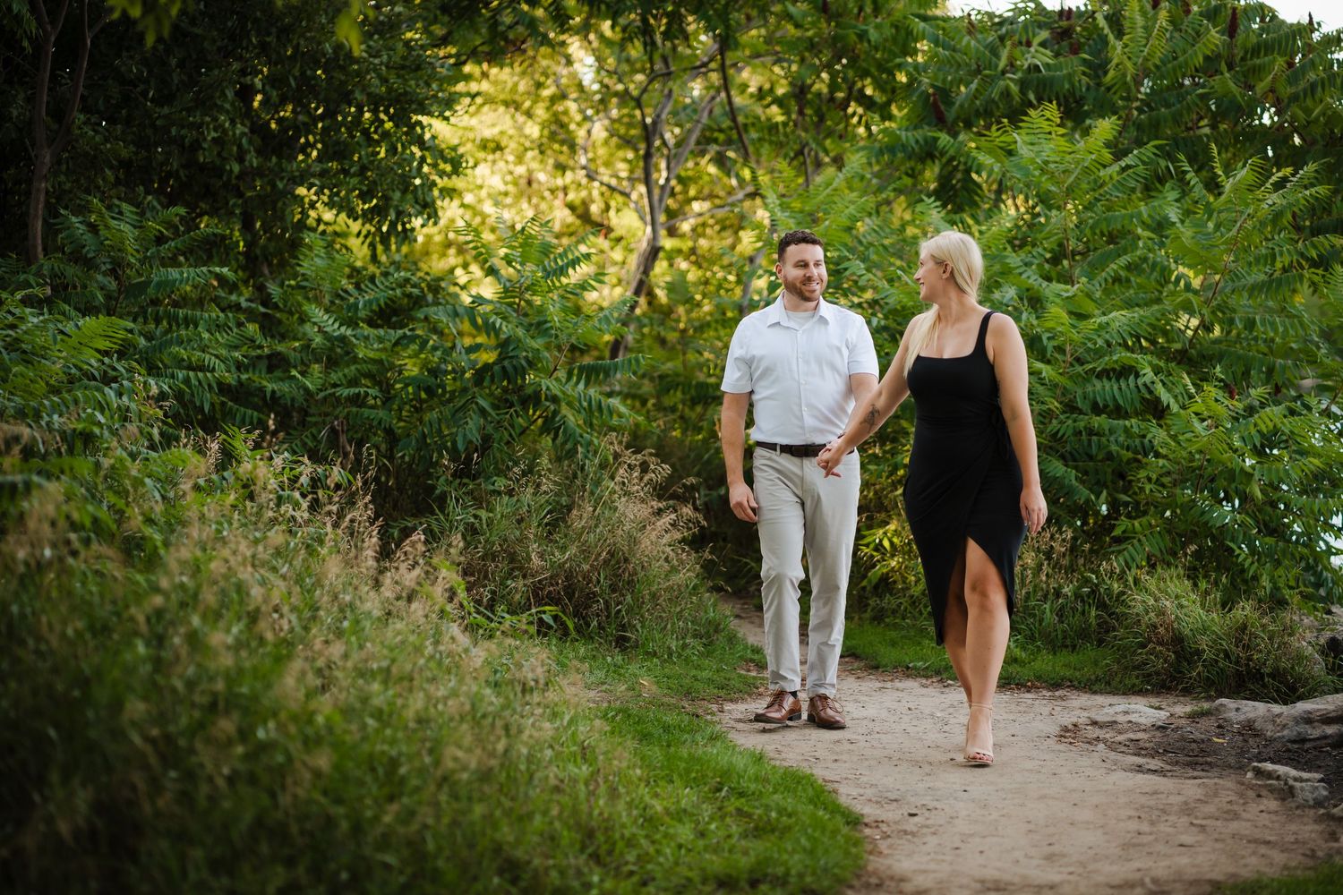 A couple enjoys a romantic walk through a scenic garden path on a sunny summer afternoon.