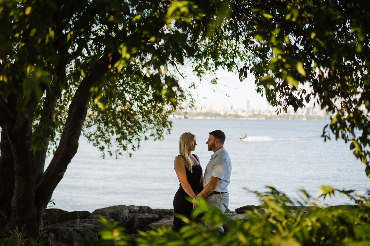 A couple poses on a scenic beach overlook during sunset with palm trees and ocean views in the background.