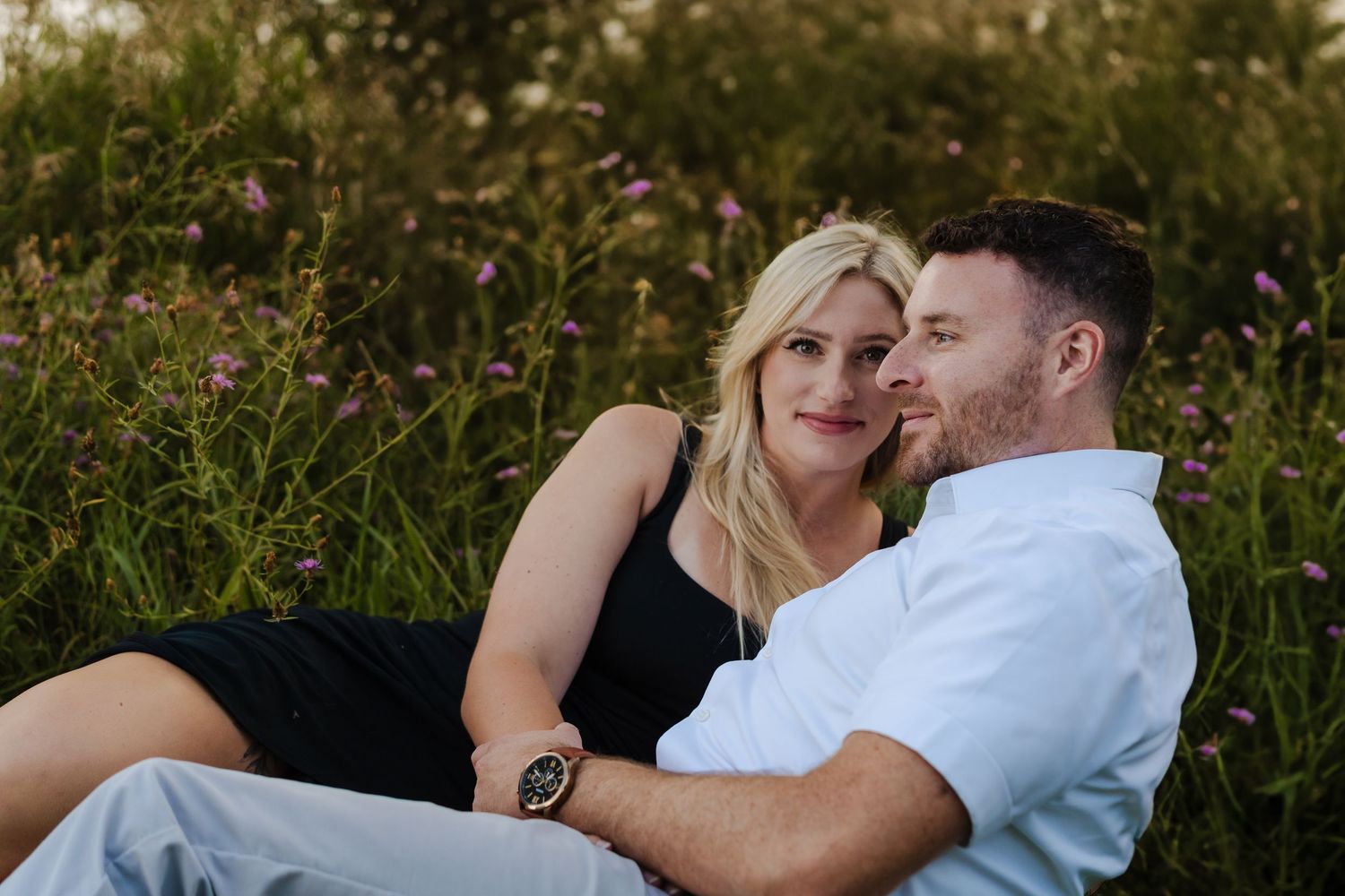 Happy couple sharing intimate moments in a wildflower meadow during sunset.