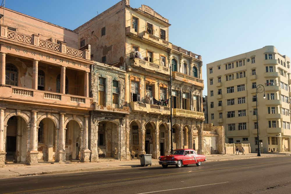 Two vintage cars parked in front of the Paseo del Prado Cuban colonial buildings in downtown Havana.