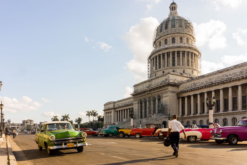 Vintage classic cars parked in front of the Capitol building in Havana, Cuba display vibrant colors against the historic architecture.