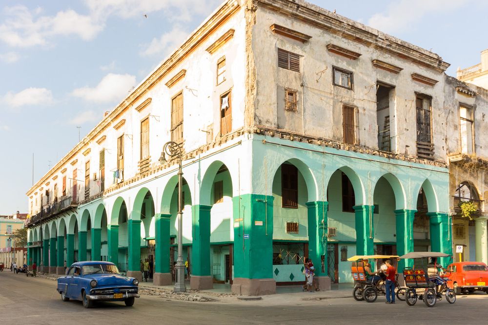 Four similar street scenes of old Cuban buildings with green painted facades and vintage cars in Havana's colonial district.