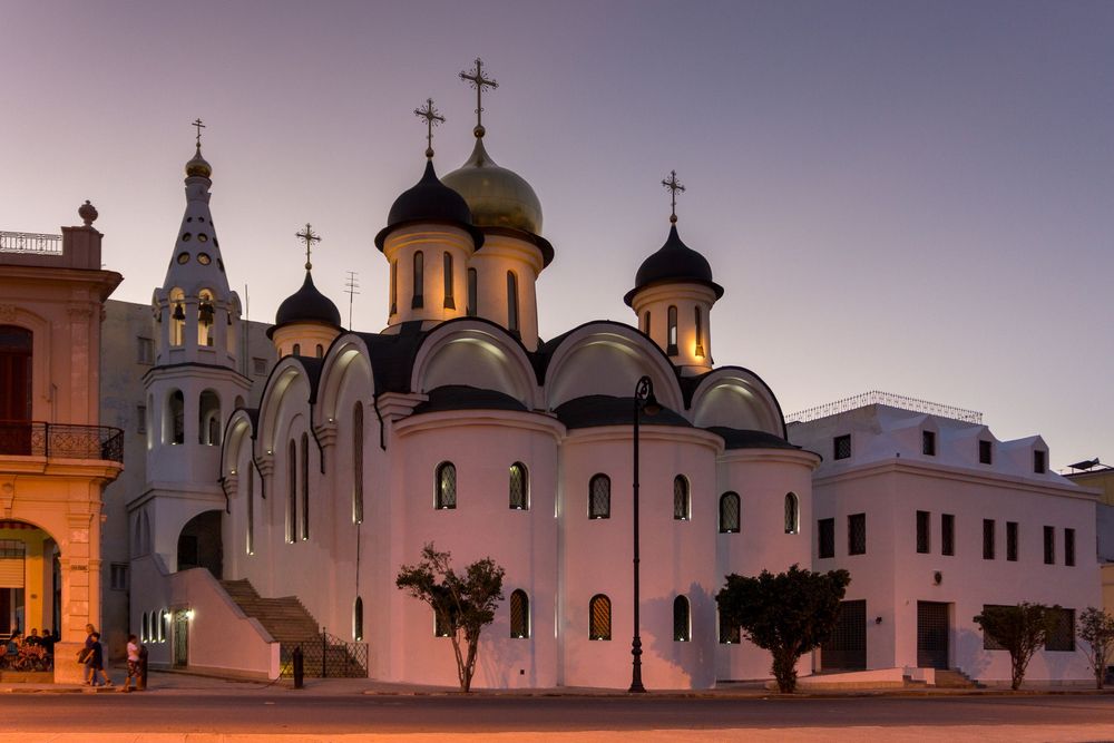 Panoramic skyline view of an Orthodox church complex with multiple domes and crosses at sunset.
