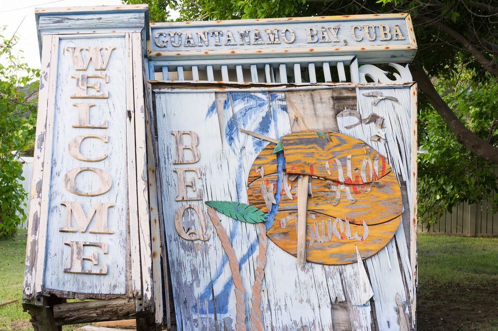 Dilapidated white garage door covered in graffiti street art featuring orange and blue designs in an outdoor setting.