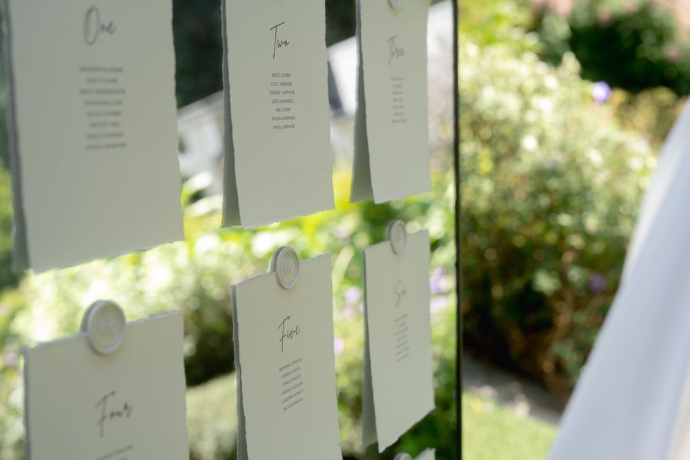 White cards or ribbons hanging from poles create a serene outdoor memorial or art installation in a garden setting.