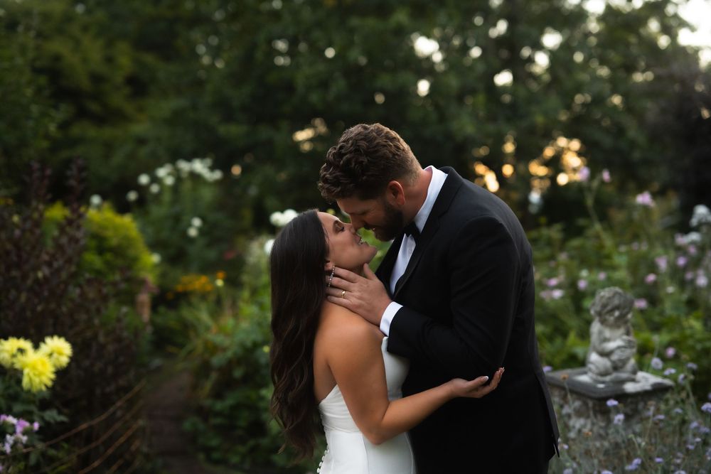 A romantic wedding couple shares a tender embrace in a lush garden setting during golden hour.